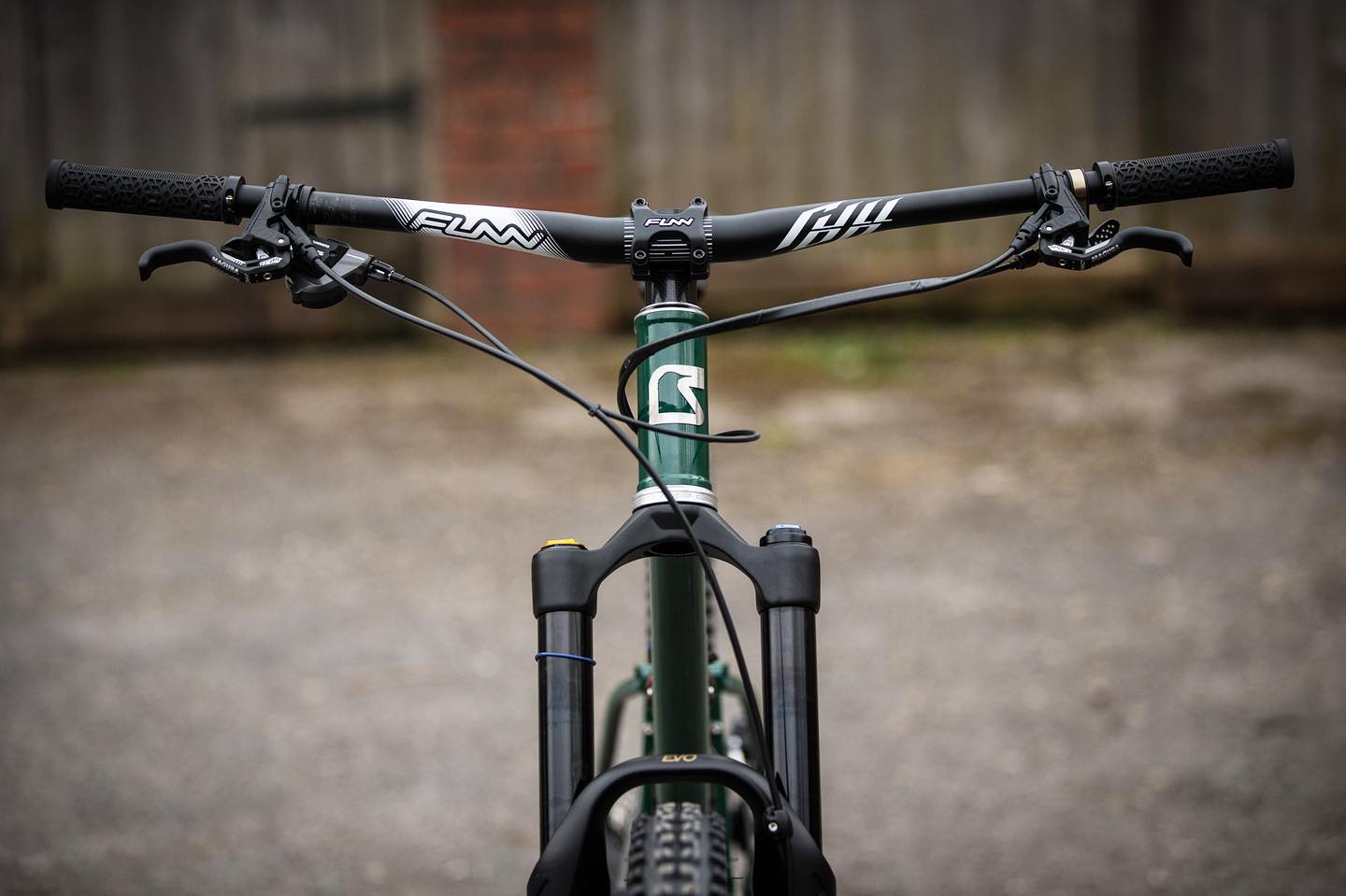 a front photo of a mountain bike equipped with funn components of black full on handlebar, black crossfire stem and a pair of black hilt grips