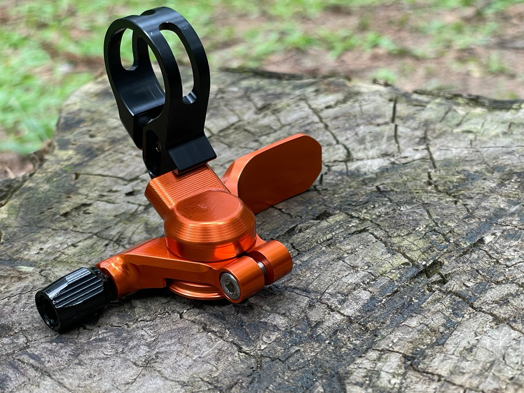 The image shows a bright orange funn updown dropper post remote lever positioned on a textured tree stump, enhancing the natural, rugged aesthetic.