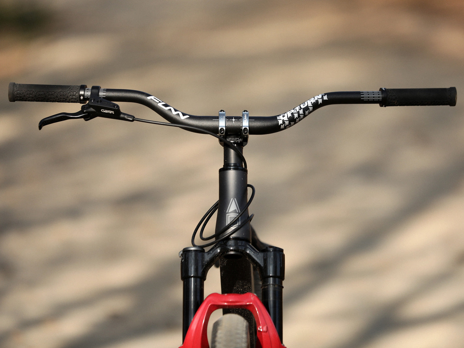 a front photo of a mountain bike equipped with funn components of black upturn handlebar, gray equalizer stem and a pair of black hilt grips