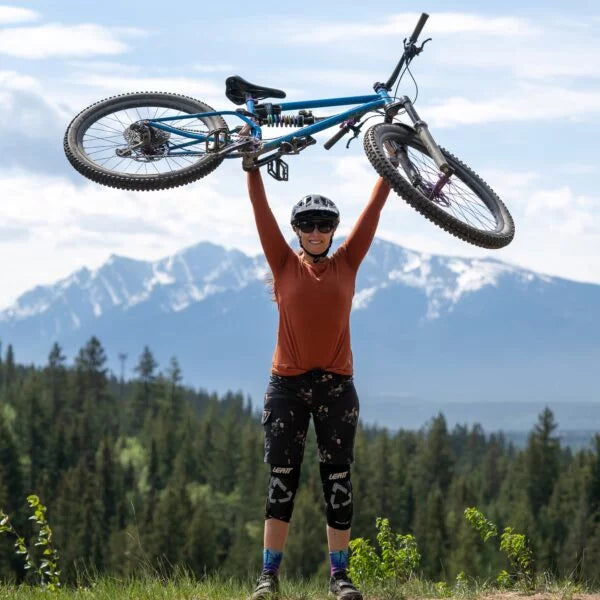 a female rider raising a bike above her shoulder