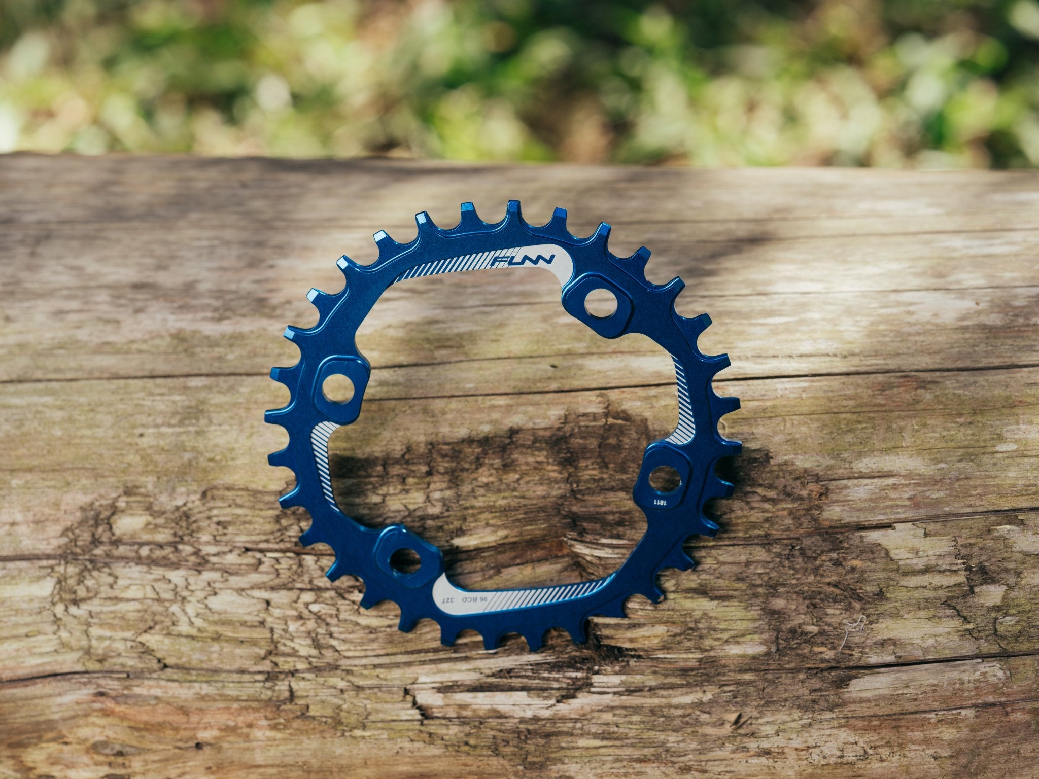 This image showcases a sleek blue Funn solo 96 bcd chainring, elegantly placed on a rustic wooden surface.