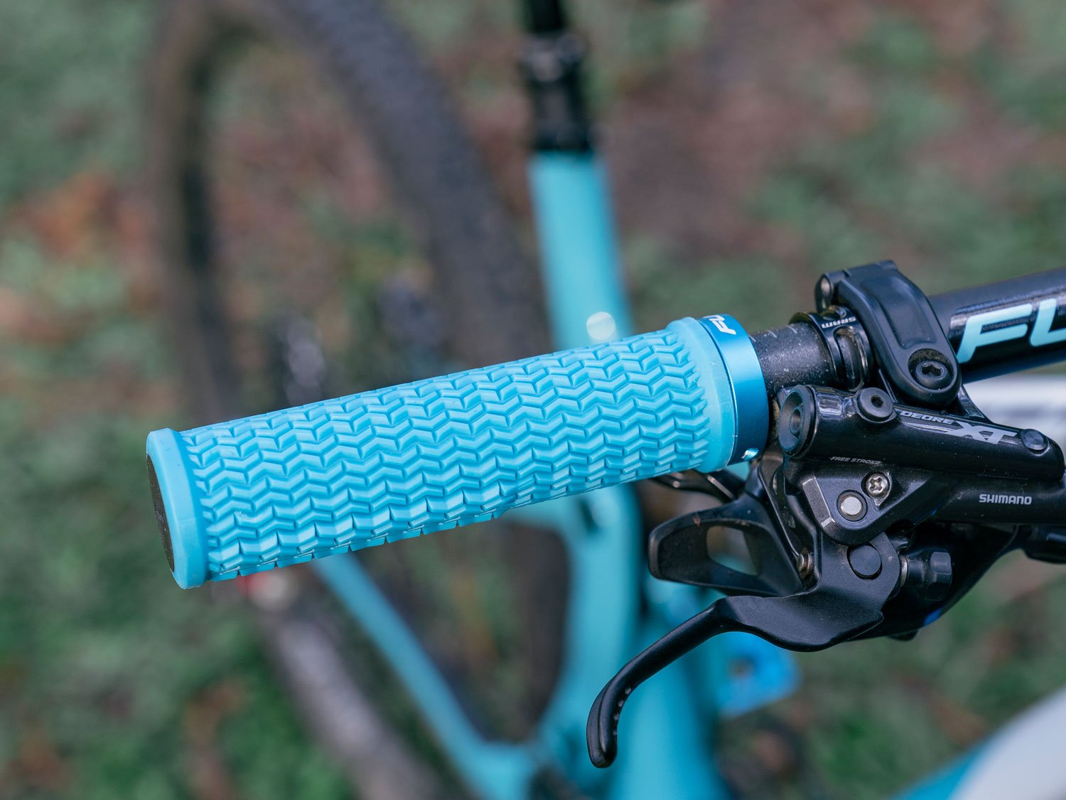 a mountain bike equipped with funn holeshot single lock on grips in turquoise color