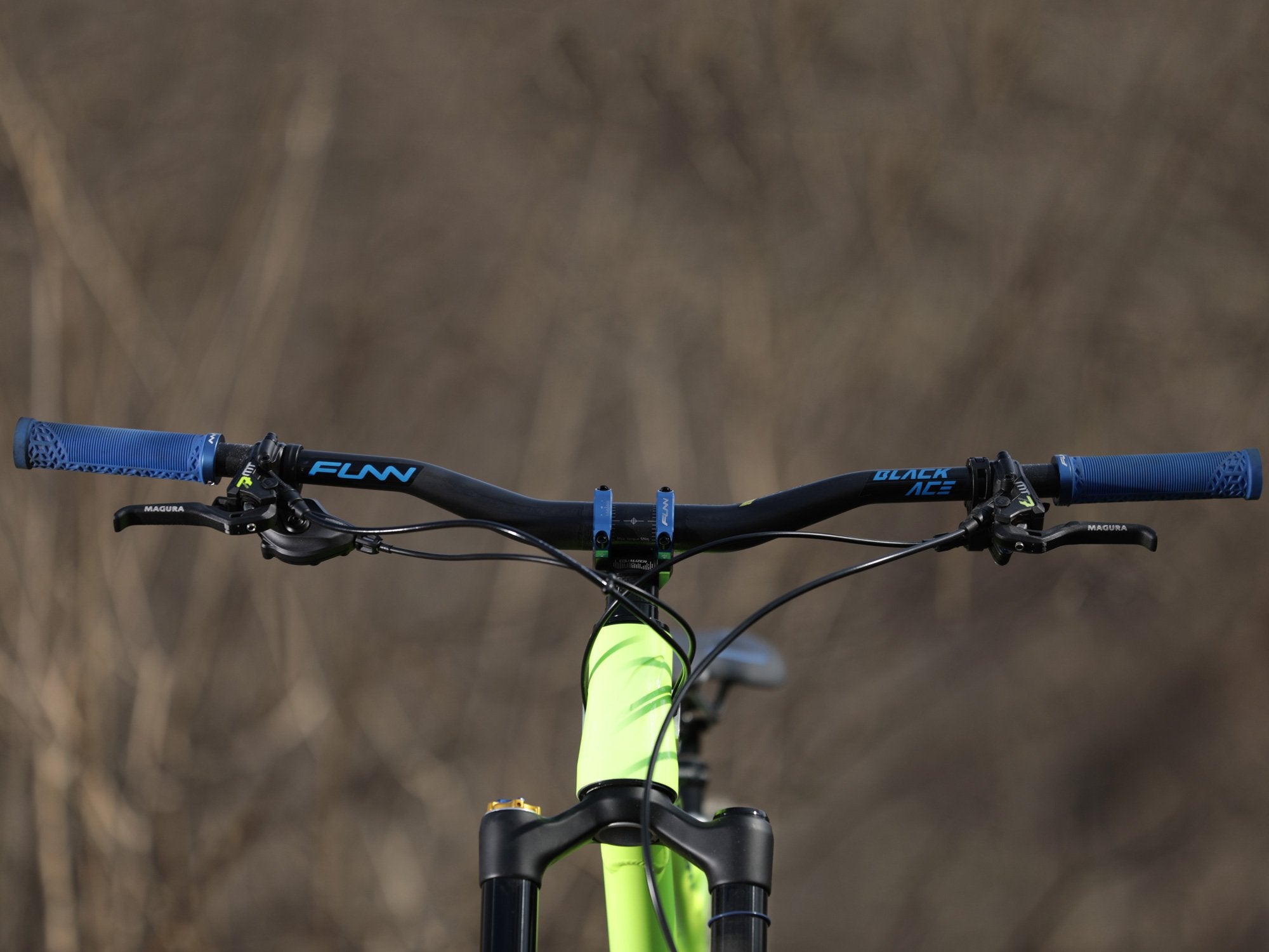 a front photo of a mountain bike equipped with funn components of black ace handlebar with blue logo stickers on the surface, blue equalizer stem and a pair of blue hilt grips