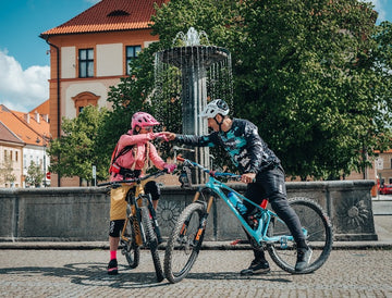 two mountain bike riders touching fists with each other