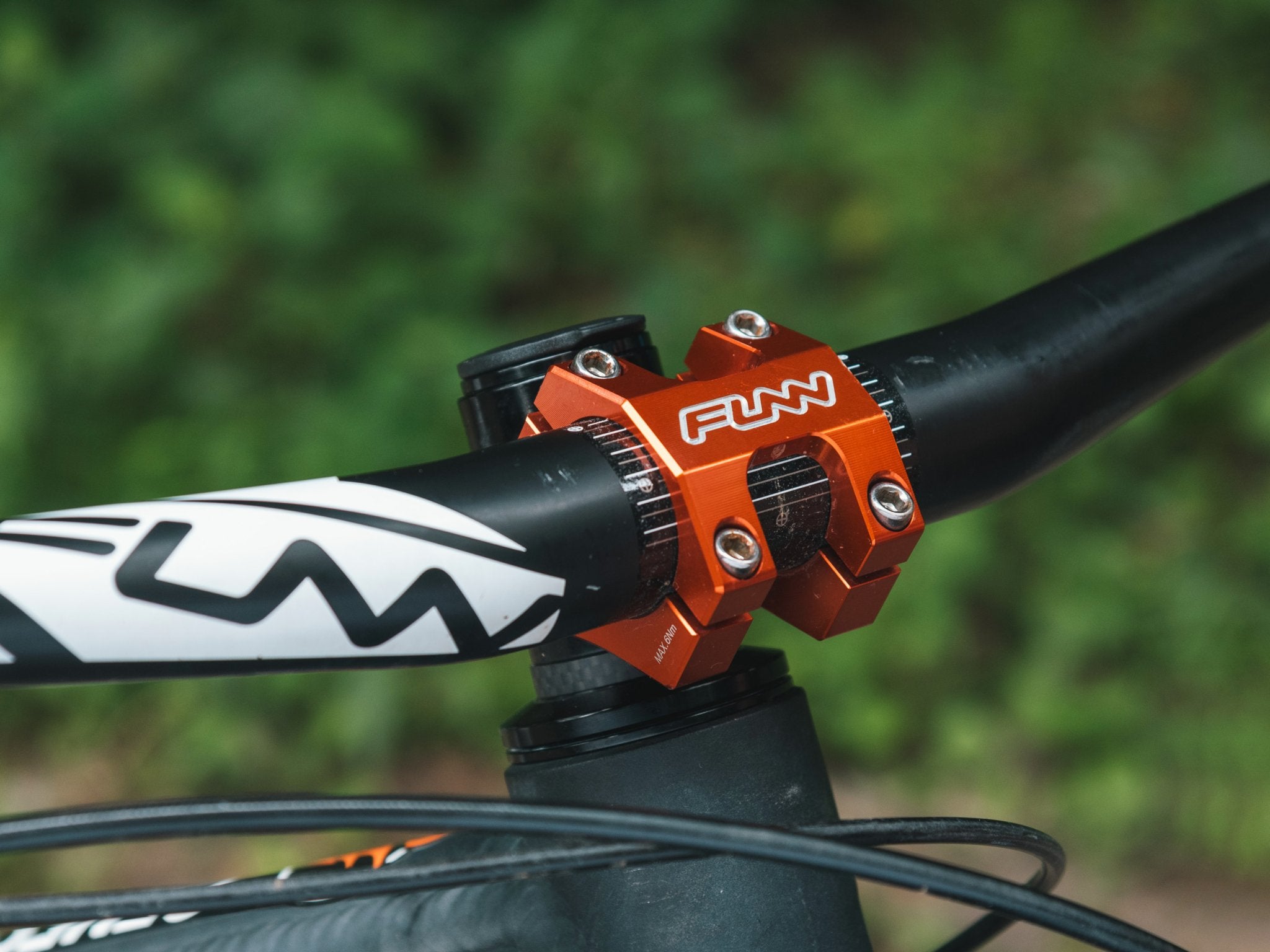 a front side of a mountain bike equipped with a black ace handlebar and an orange funnduro bike stem