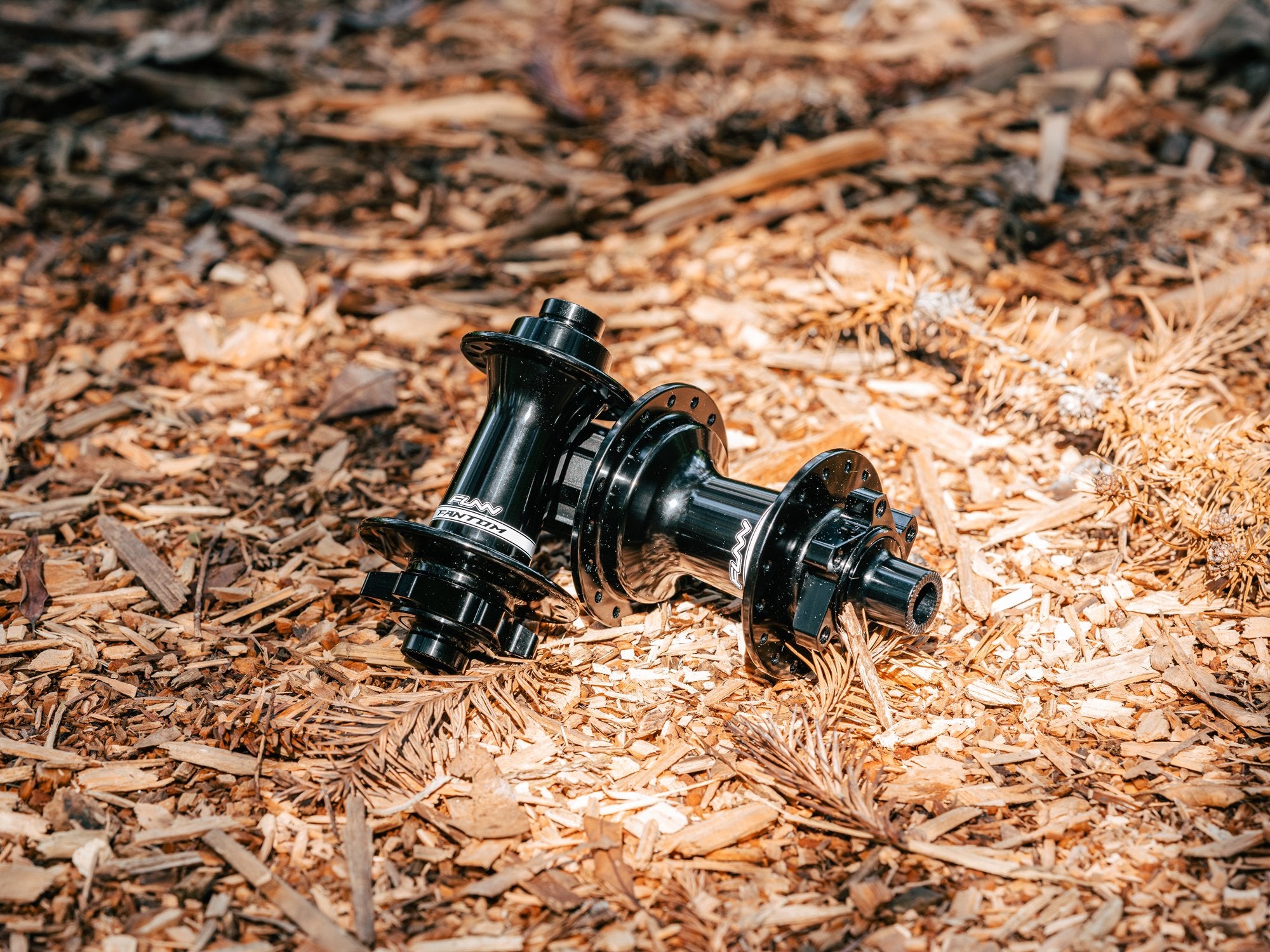 two Funn Fantom hubs lying on a bed of wood chips and dried leaves, creating an earthy and natural setting.