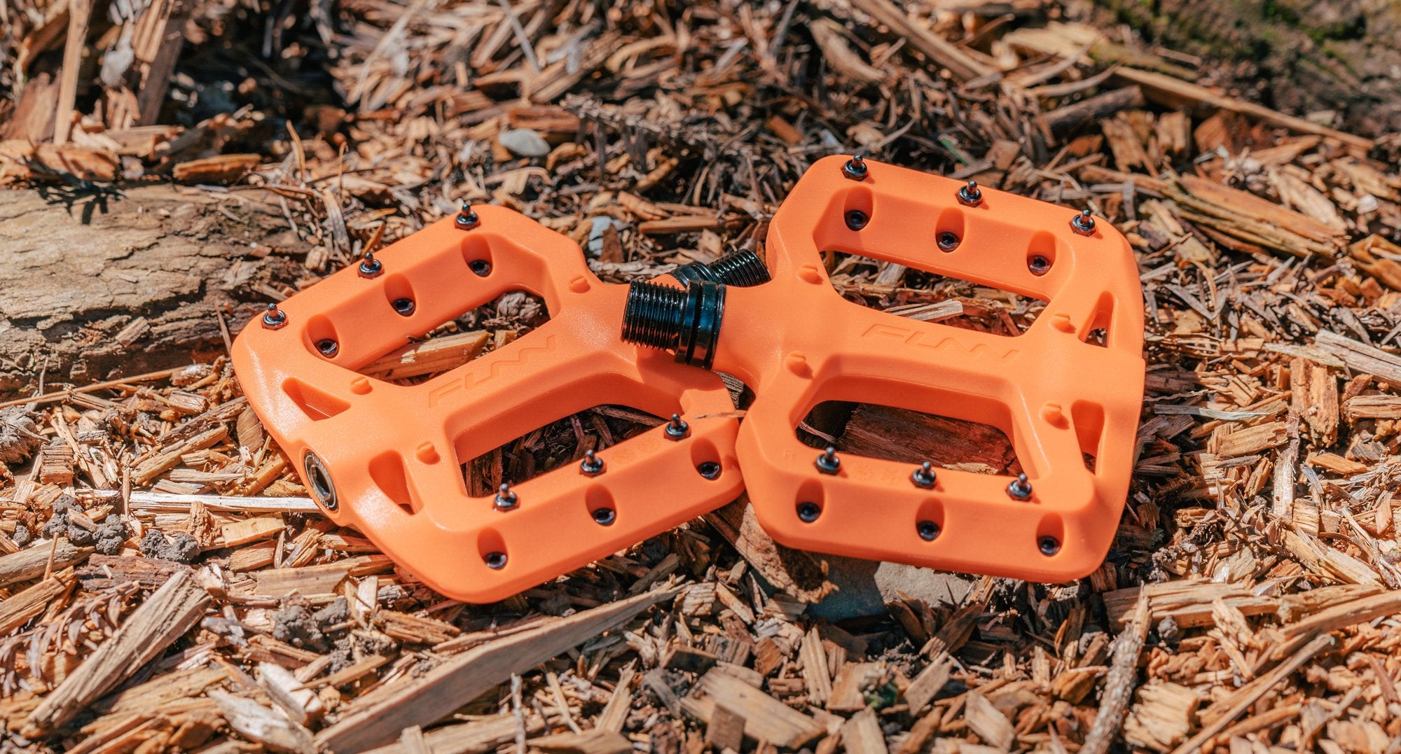 a pair of orange funn taipan s plastic flat pedals on the ground