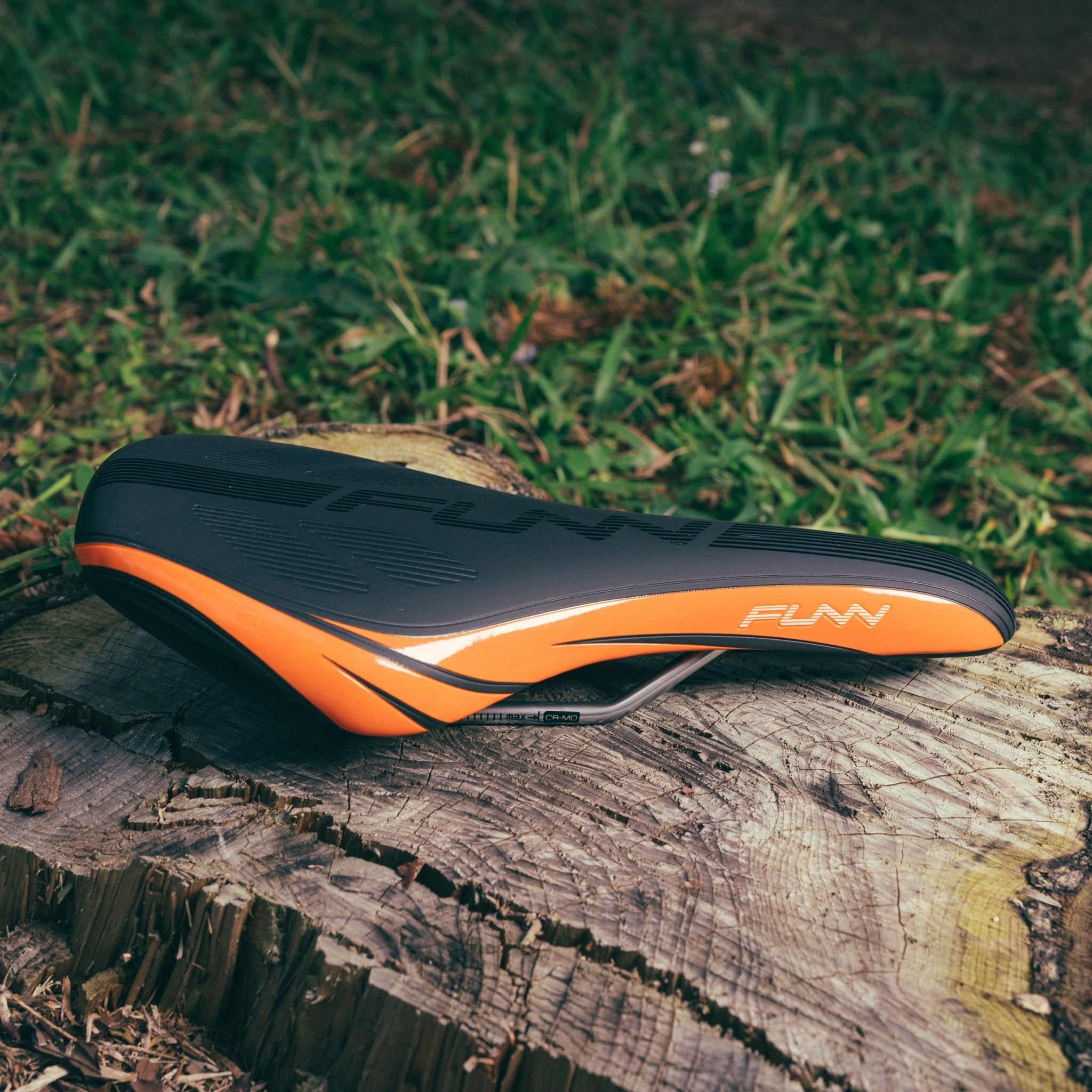 FUNN Adlib HD Saddle, black and orange ergonomic MTB bike seat with padded synthetic cover on trail stump