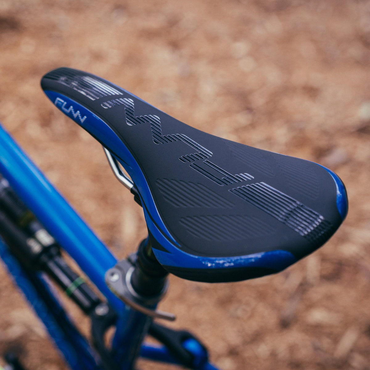 FUNN Adlib Saddle, black and blue ergonomic bike seat with textured surface on a blue mountain bike for trail riding