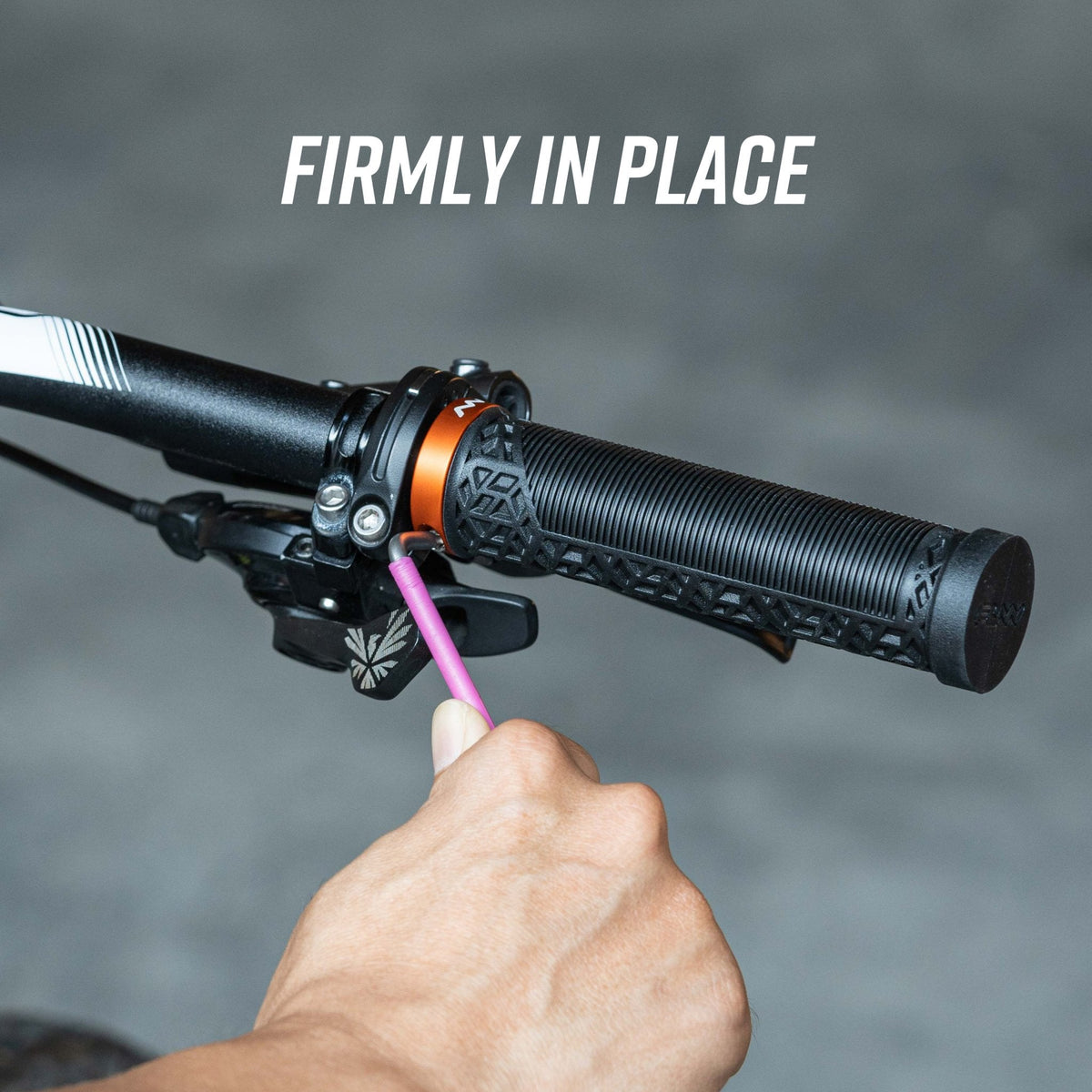 FUNN alloy bike grip clamping rings securing Hilt / Holeshot black handlebar grip with orange lock-on collar being tightened