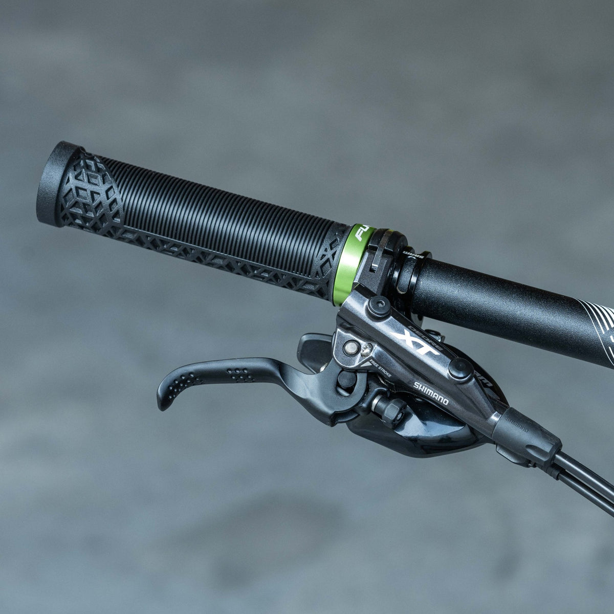 FUNN alloy bike grip clamping ring in green securing black Hilt / Holeshot handlebar grip beside Shimano XT brake lever