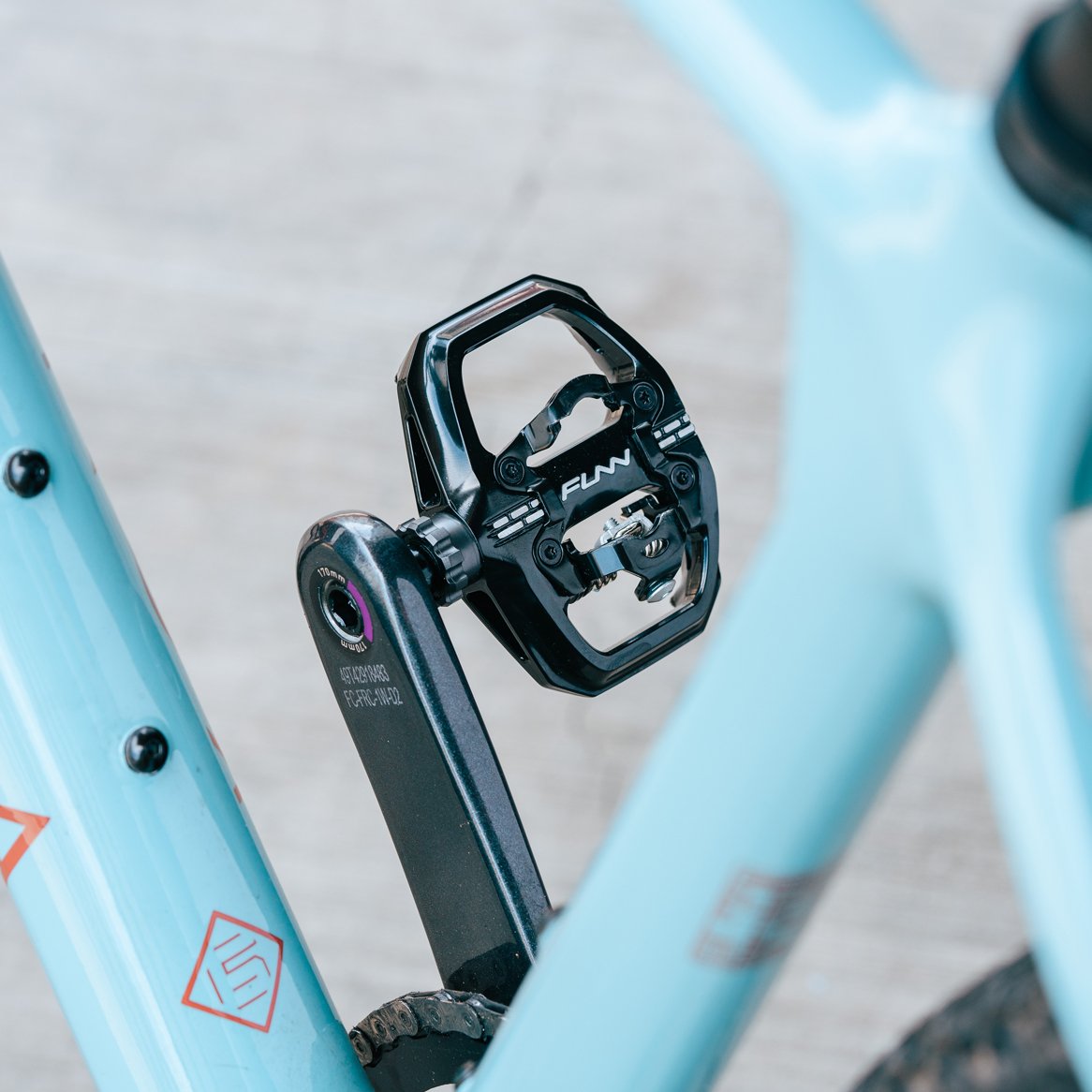 Black FUNN Clast Clip-In Pedals mounted on a light blue bike, alloy platform design for secure, high-performance cycling