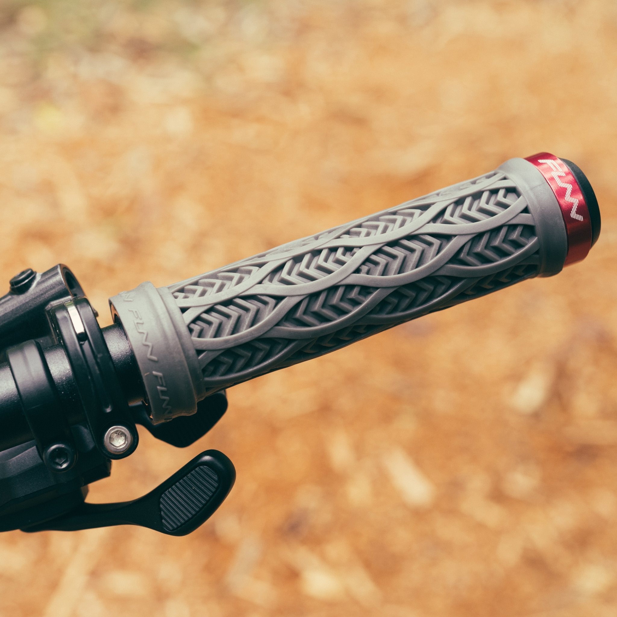 FUNN Combat III Lock-On Grips in gray rubber with textured pattern and red clamp, mounted on a mountain bike handlebar