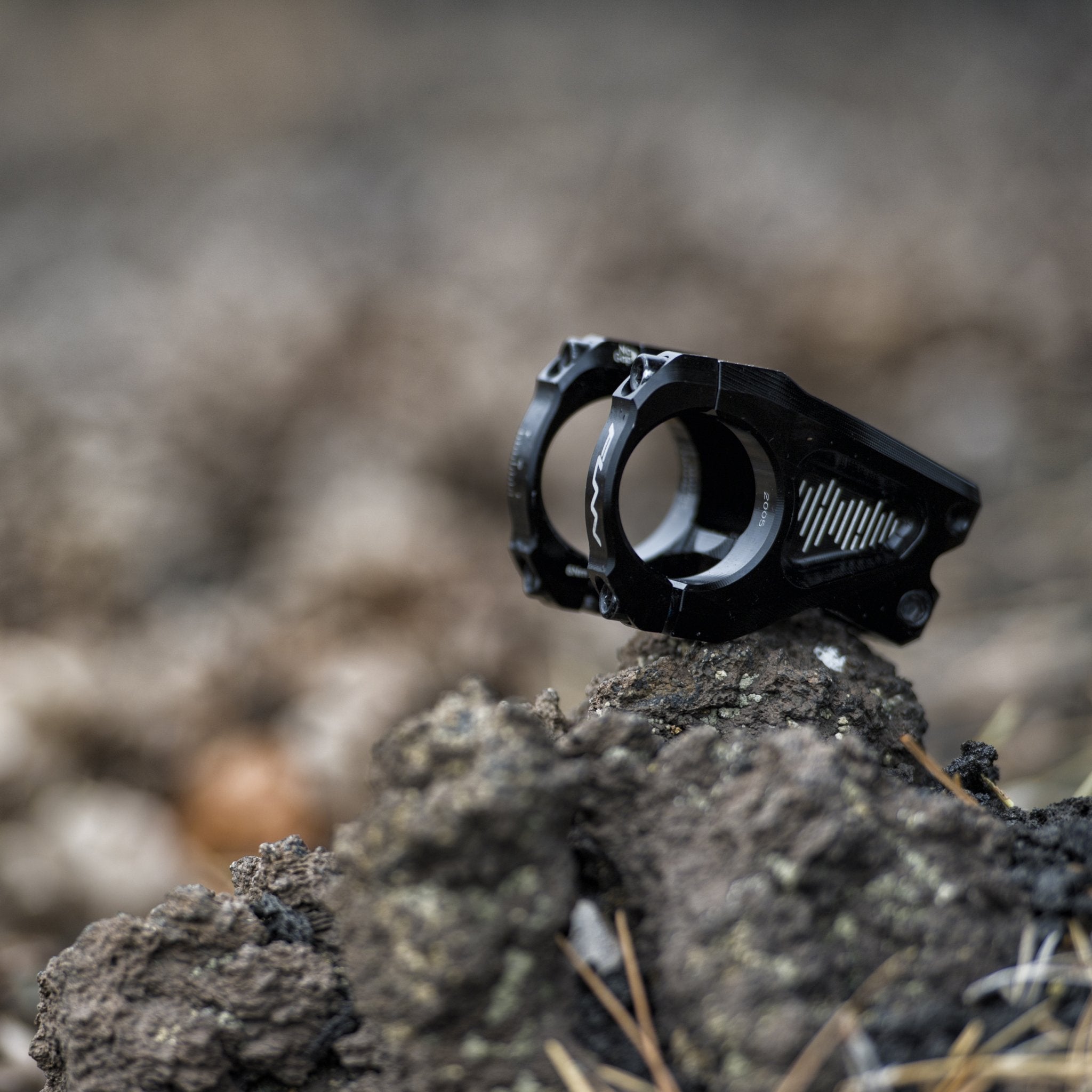 Black aluminum FUNN Equalizer Stem bike handlebar clamp with CNC details, shown on rocky trail terrain