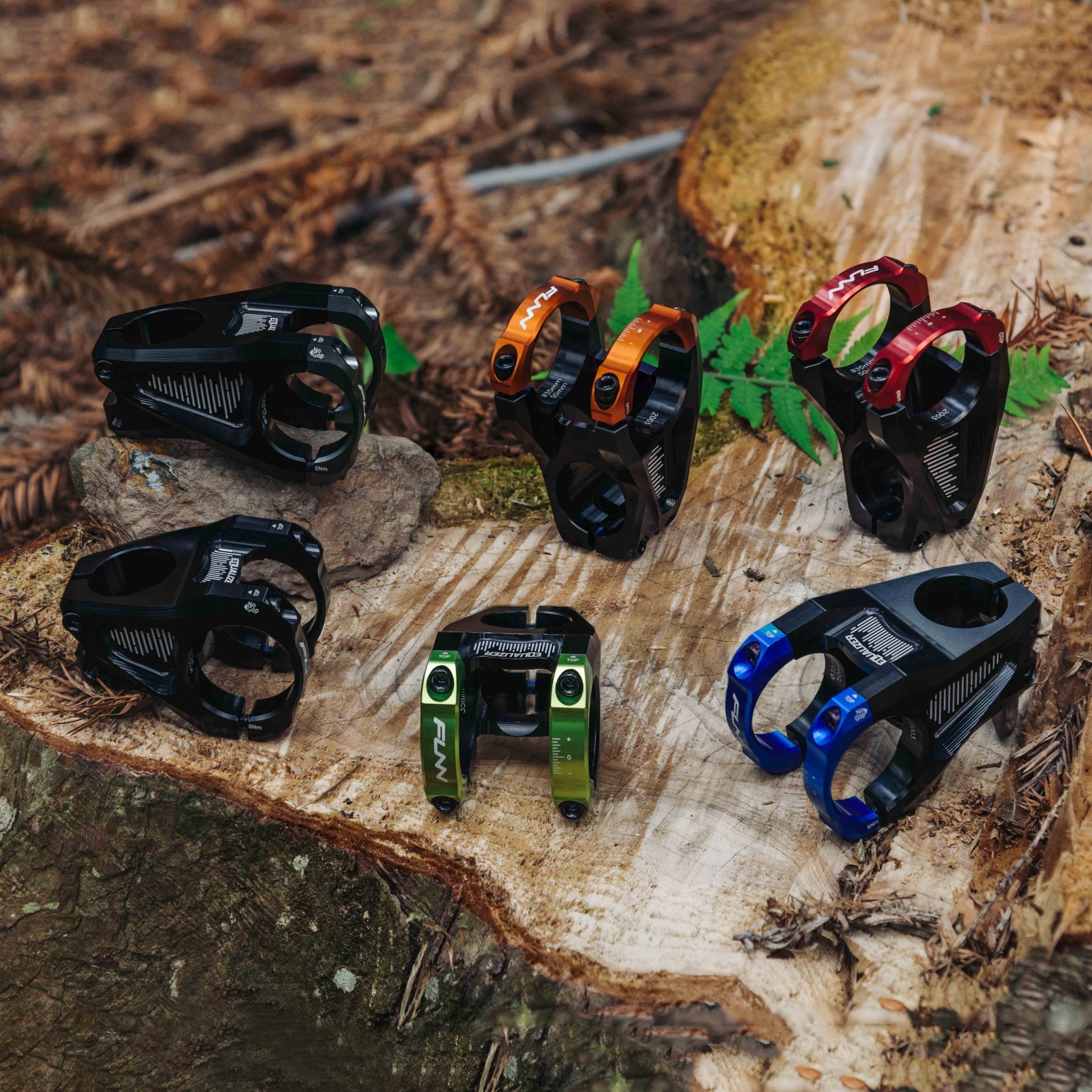 FUNN Equalizer Stem with colorful clamps in red, blue, orange and green, CNC alloy mountain bike handlebar stems on a log