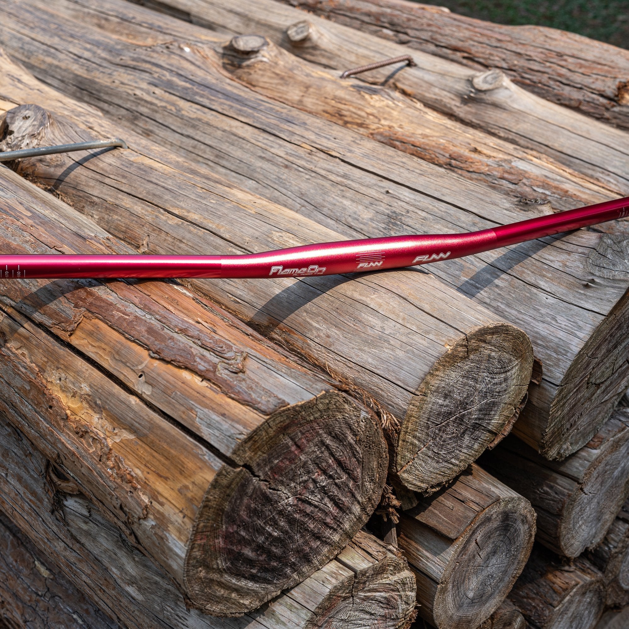 Red FUNN Flame On Flat Handlebar, lightweight alloy MTB bar with slight rise, shown on stacked wooden logs