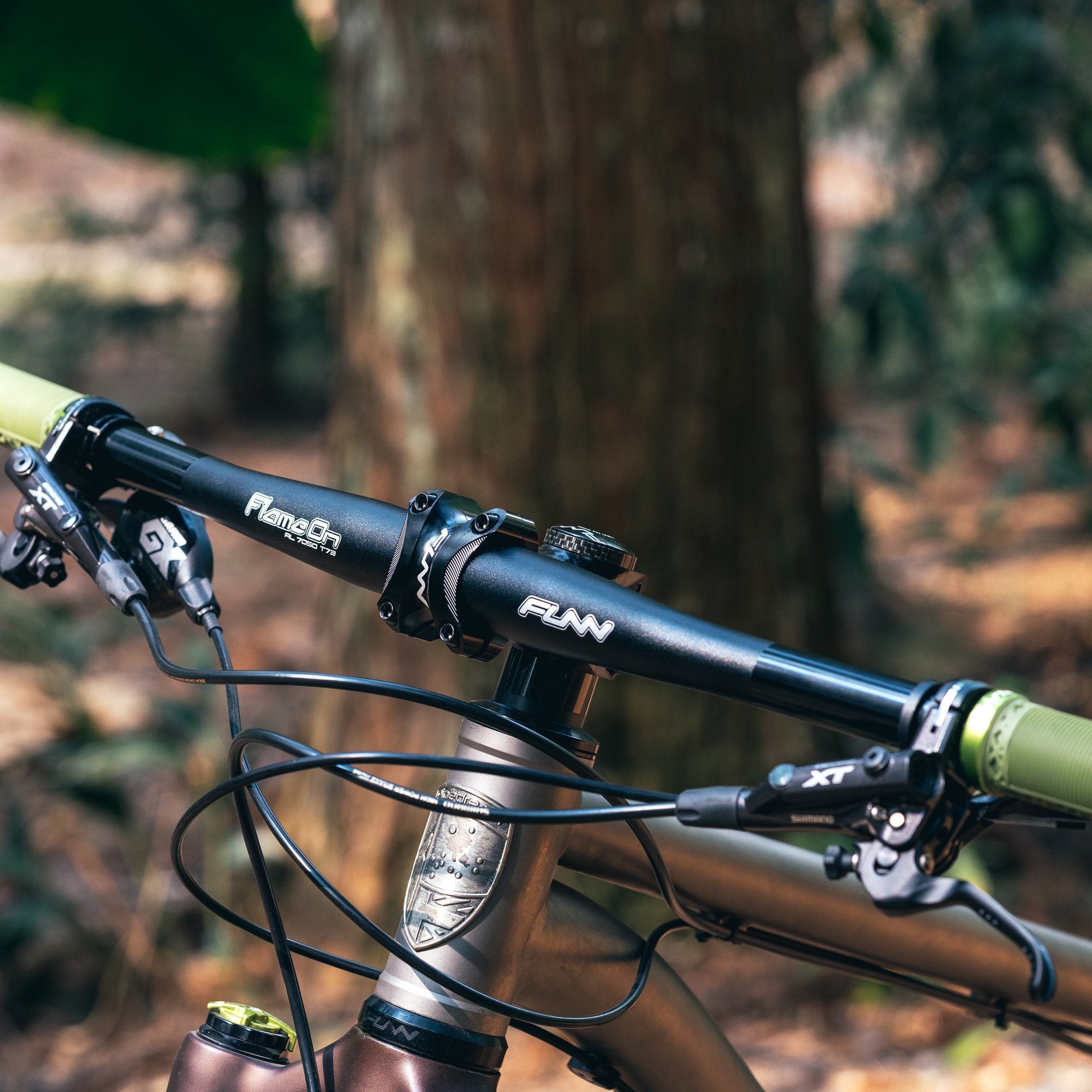 FUNN Flame On Flat Handlebar 710mm, black alloy flat bar on mountain bike with green grips and hydraulic brake levers