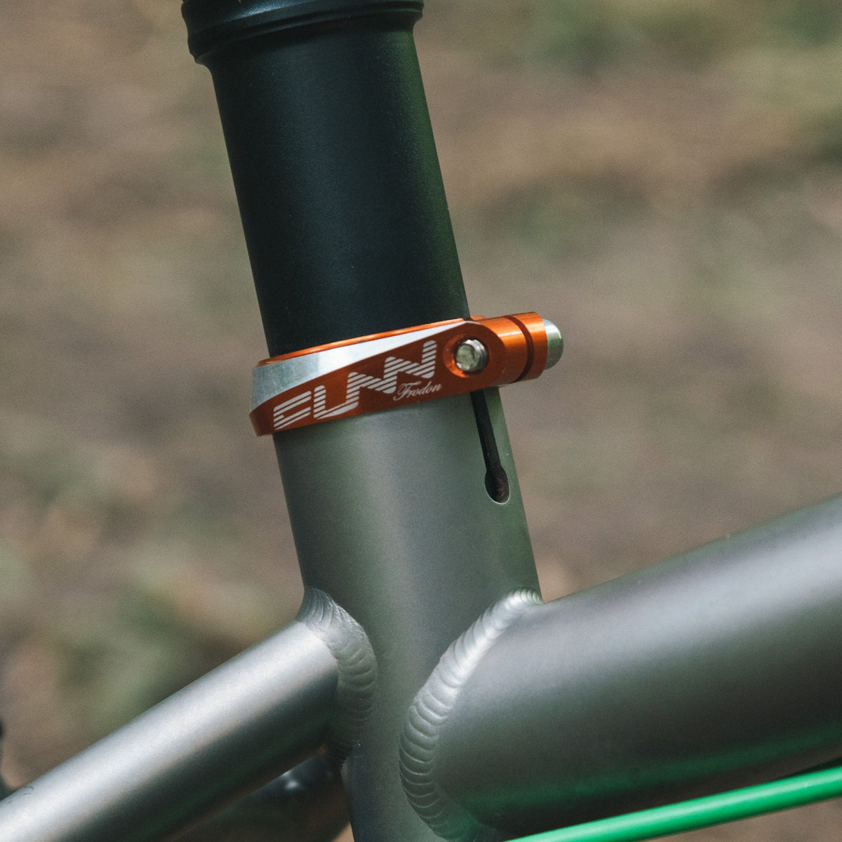 FUNN Frodon Seat Clamp, orange CNC alloy, securing black seatpost on silver bike frame for precise saddle height adjustment