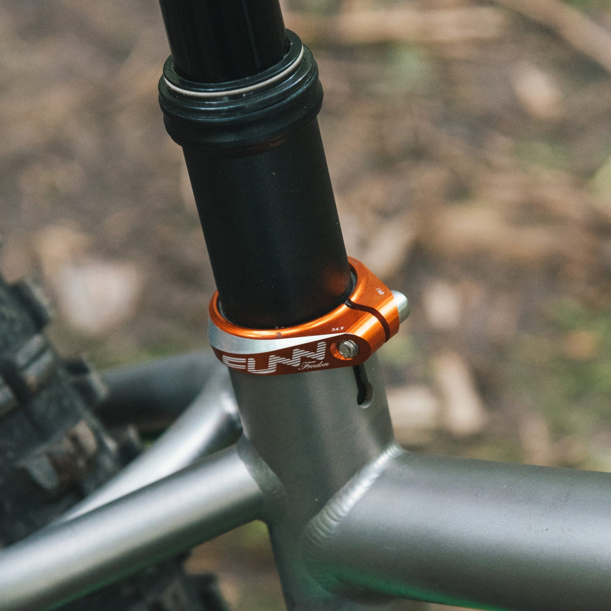 FUNN Frodon Seat Clamp, orange CNC alloy clamp securing black seatpost on silver mountain bike frame