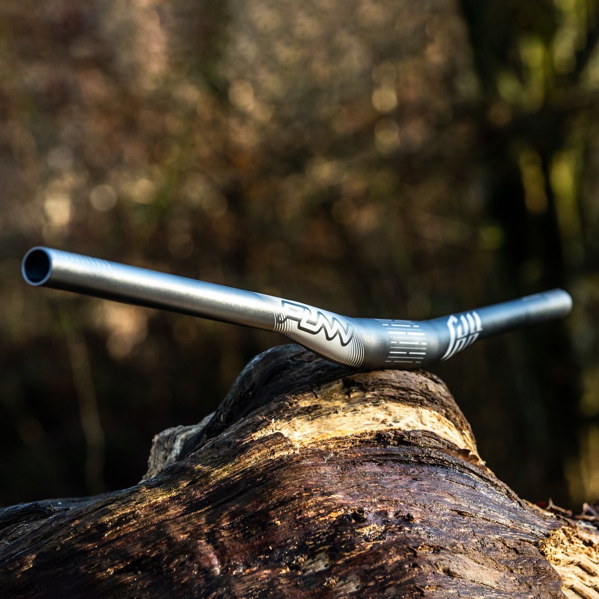 FUNN Full On Riser Handler 31.8mm alloy handlebar with 7mm rise, matte black with white graphics, resting on a log outdoors