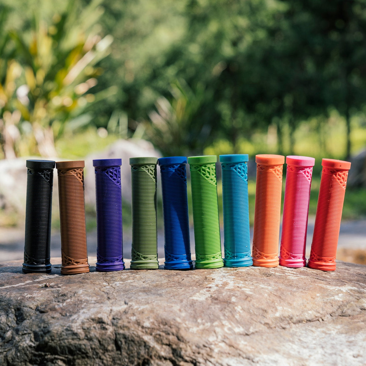 Colorful FUNN Hilt ES Slip-On Grips, ribbed rubber bike handlebar grips lined up outdoors for secure, comfortable control