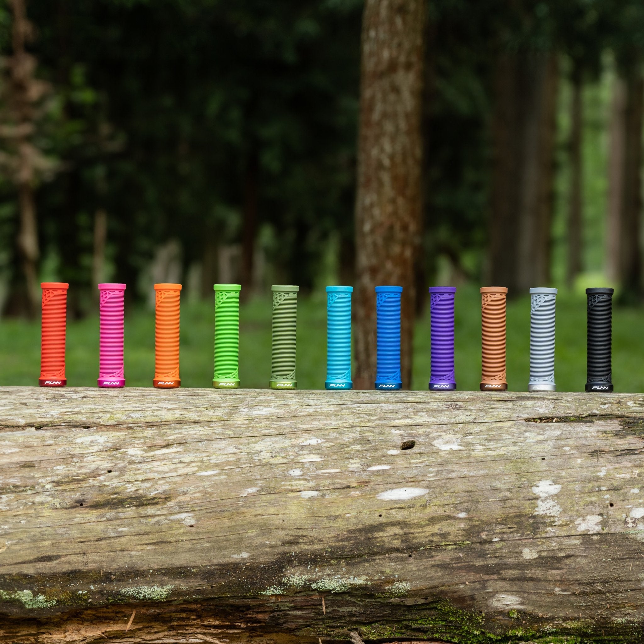 FUNN Hilt JR Lock-On Grips in bright youth grom colors, slim rubber bike handlebar grips lined up on a log outdoors