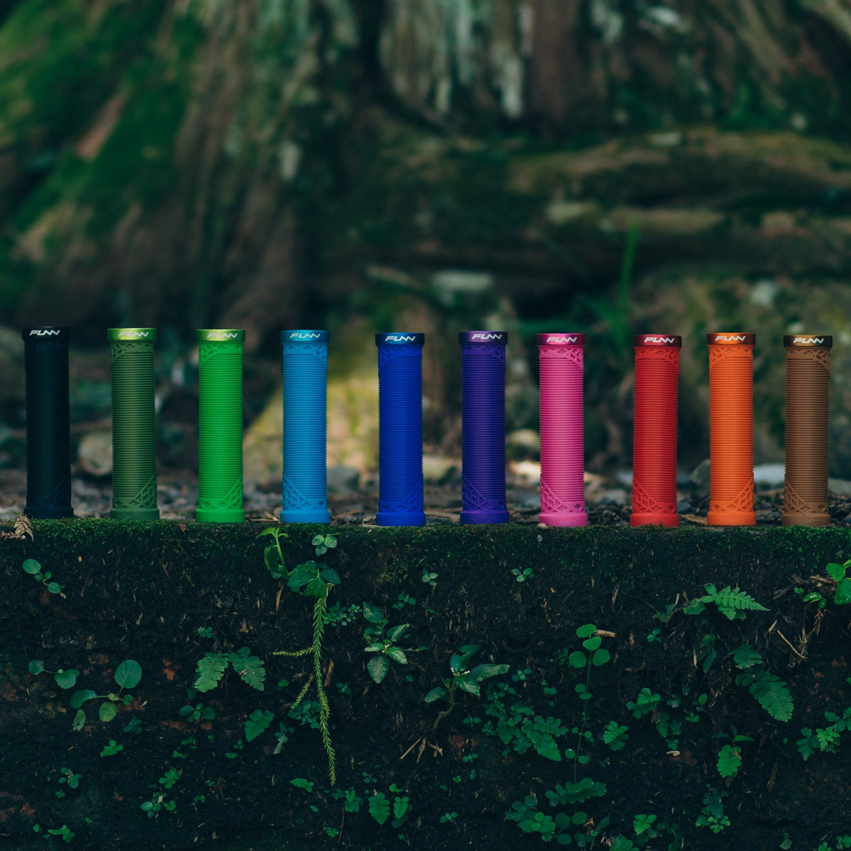 FUNN Hilt Lock-On Grips in multiple bright colors, ribbed rubber mountain bike handlebar grips displayed outdoors on moss.