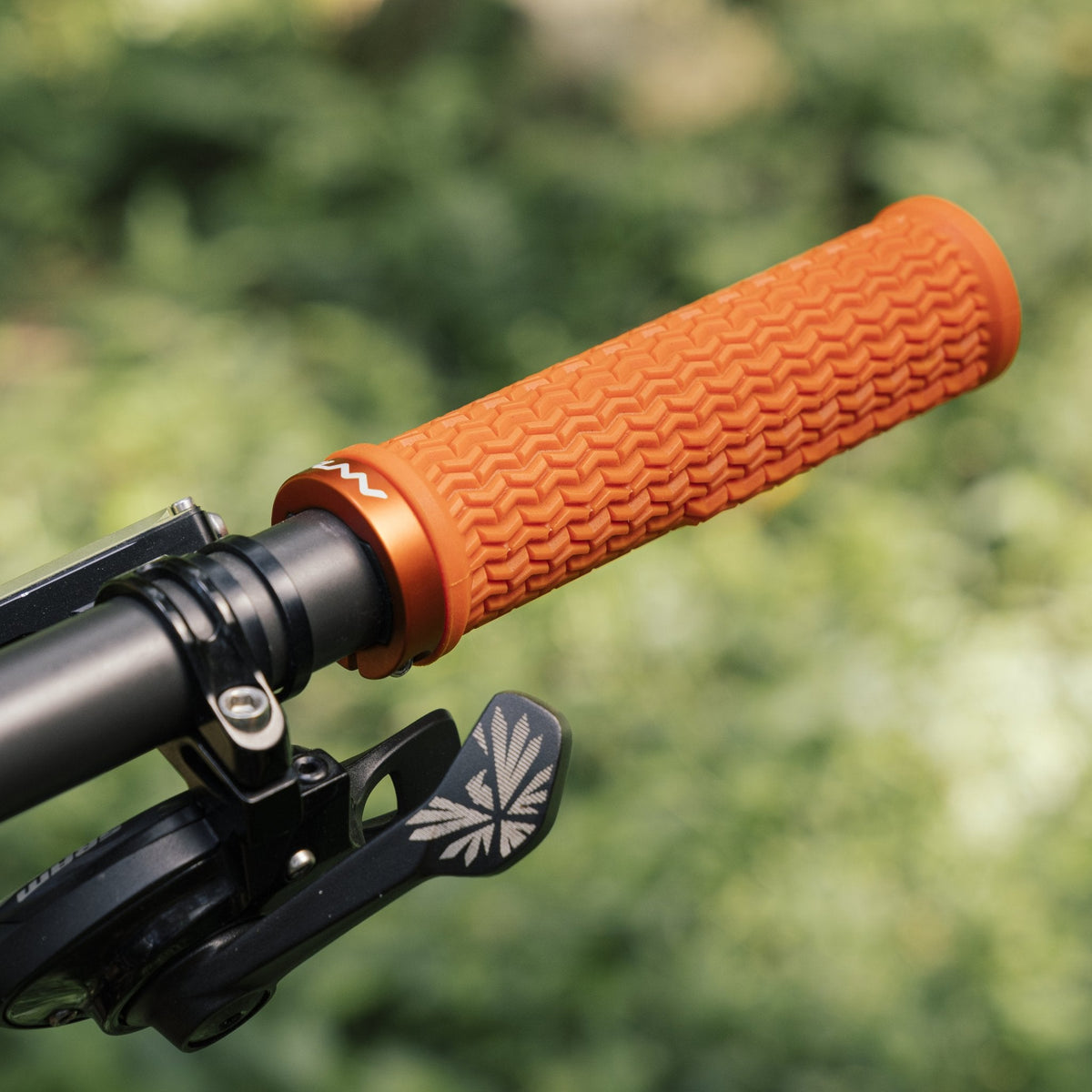 Funn Holeshot Lock-On Grips in bright orange with textured rubber pattern mounted on a black bike handlebar for secure control