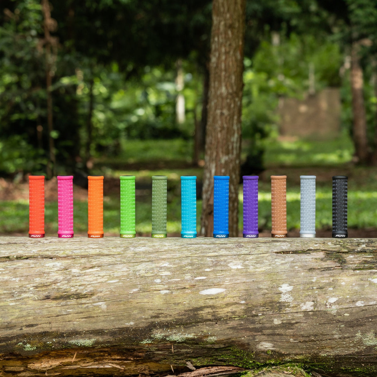 FUNN Holeshot Lock-On Grips in 11 colorways, textured rubber bike handlebar grips lined up outdoors on a log
