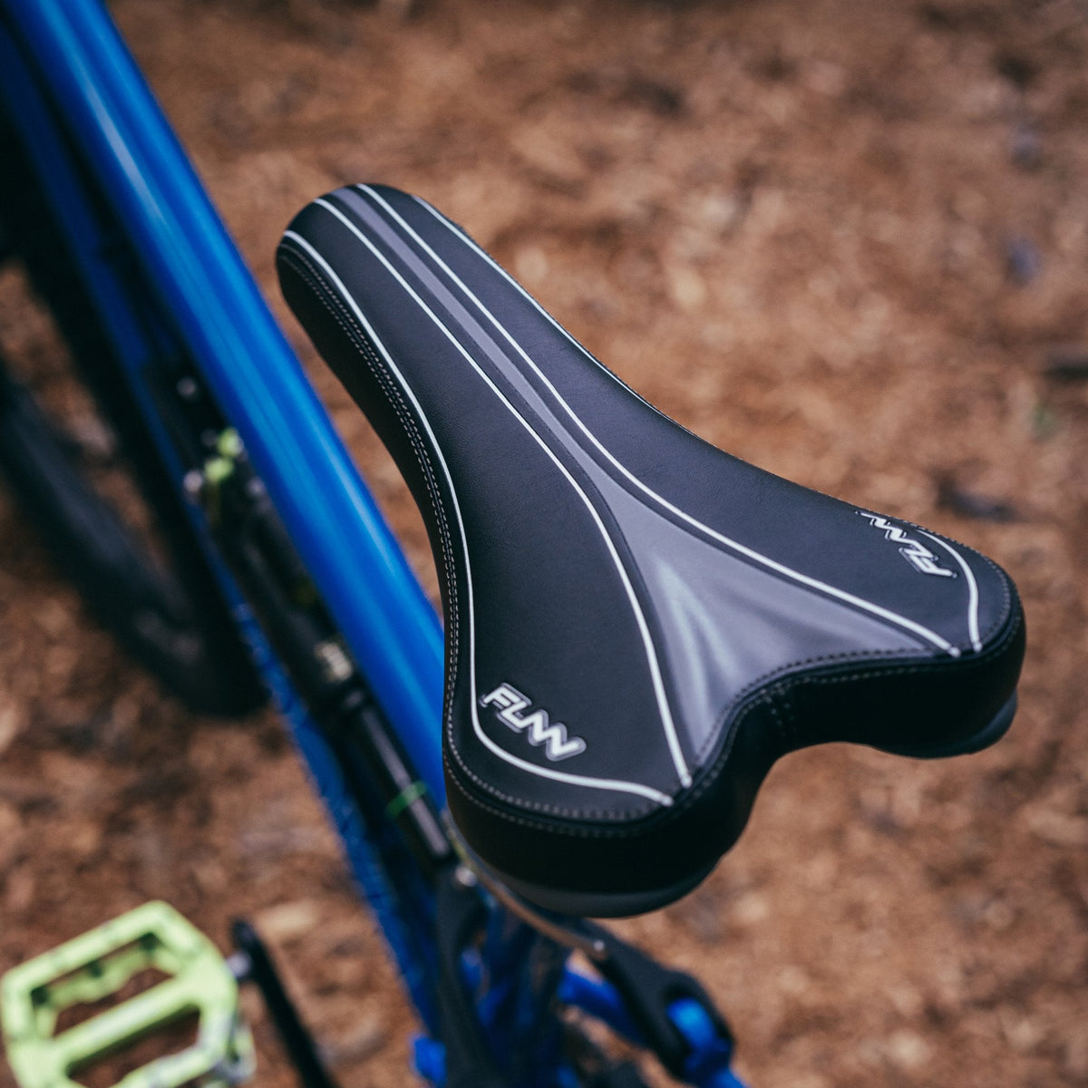 FUNN Launch II Saddle, black ergonomic bike seat with white accents, padded synthetic cover mounted on blue mountain bike