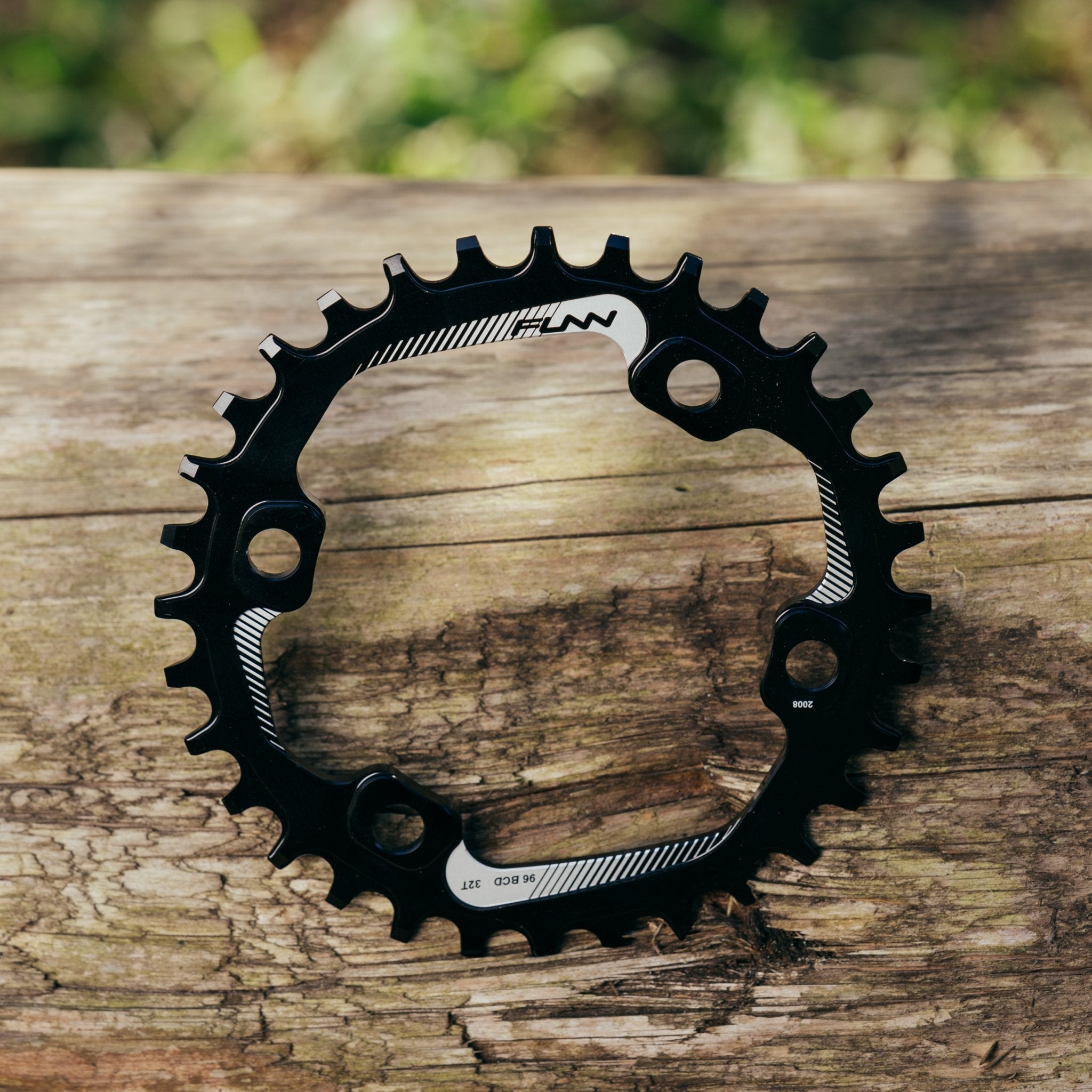 Black aluminum FUNN Solo 96 Narrow-Wide Chainring with offset teeth and 4-bolt mounting, shown on rustic wooden background