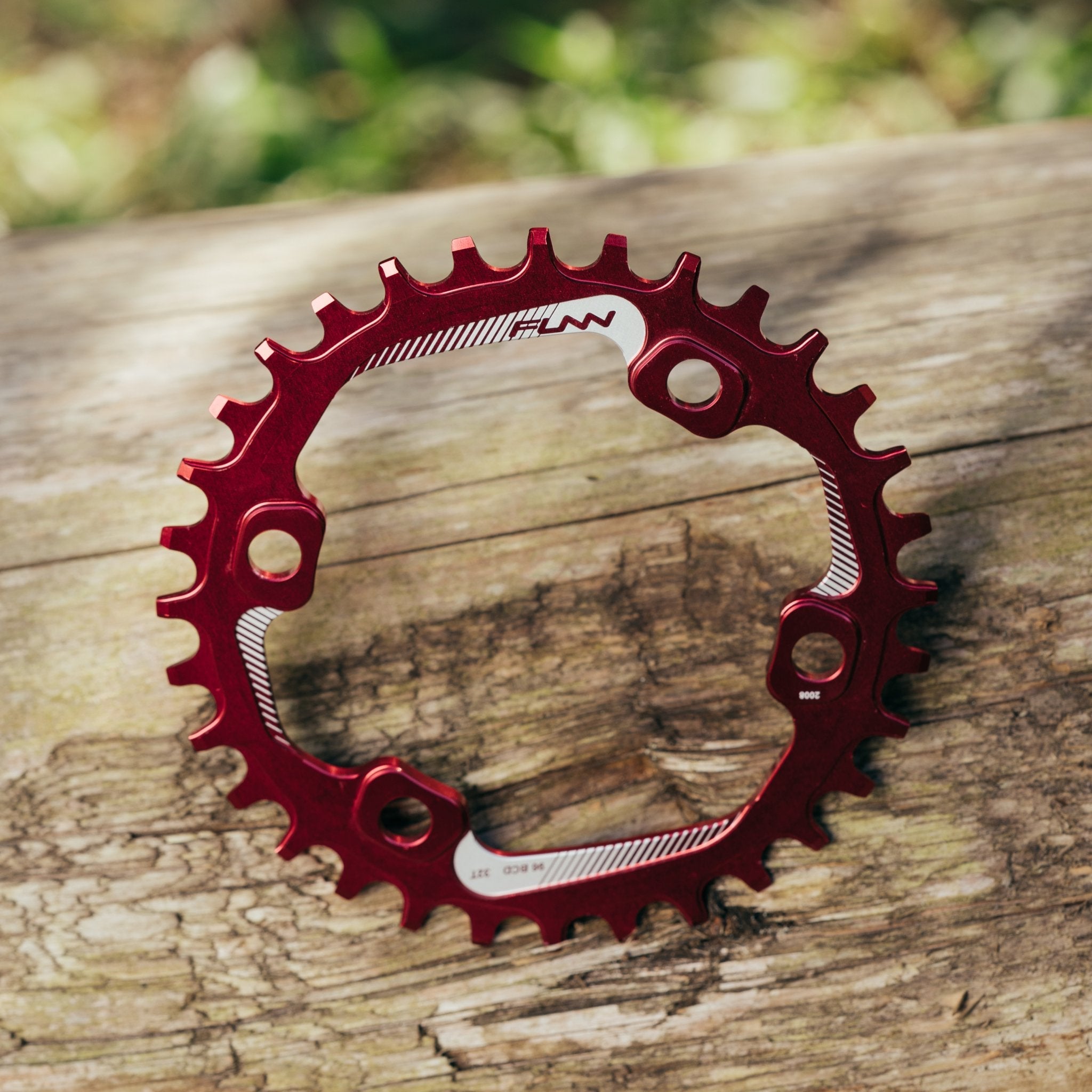 Red aluminum FUNN Solo 96 Narrow-Wide Chainring with offset teeth and mounting holes, shown on rustic wooden background
