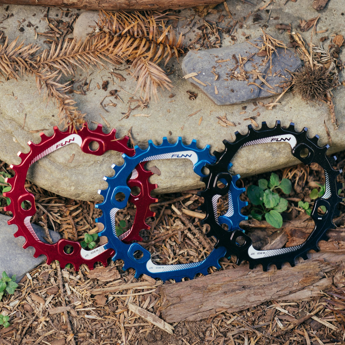FUNN Solo 96 Narrow-Wide Chainring in red, blue and black anodized alloy, round MTB chainrings displayed outdoors