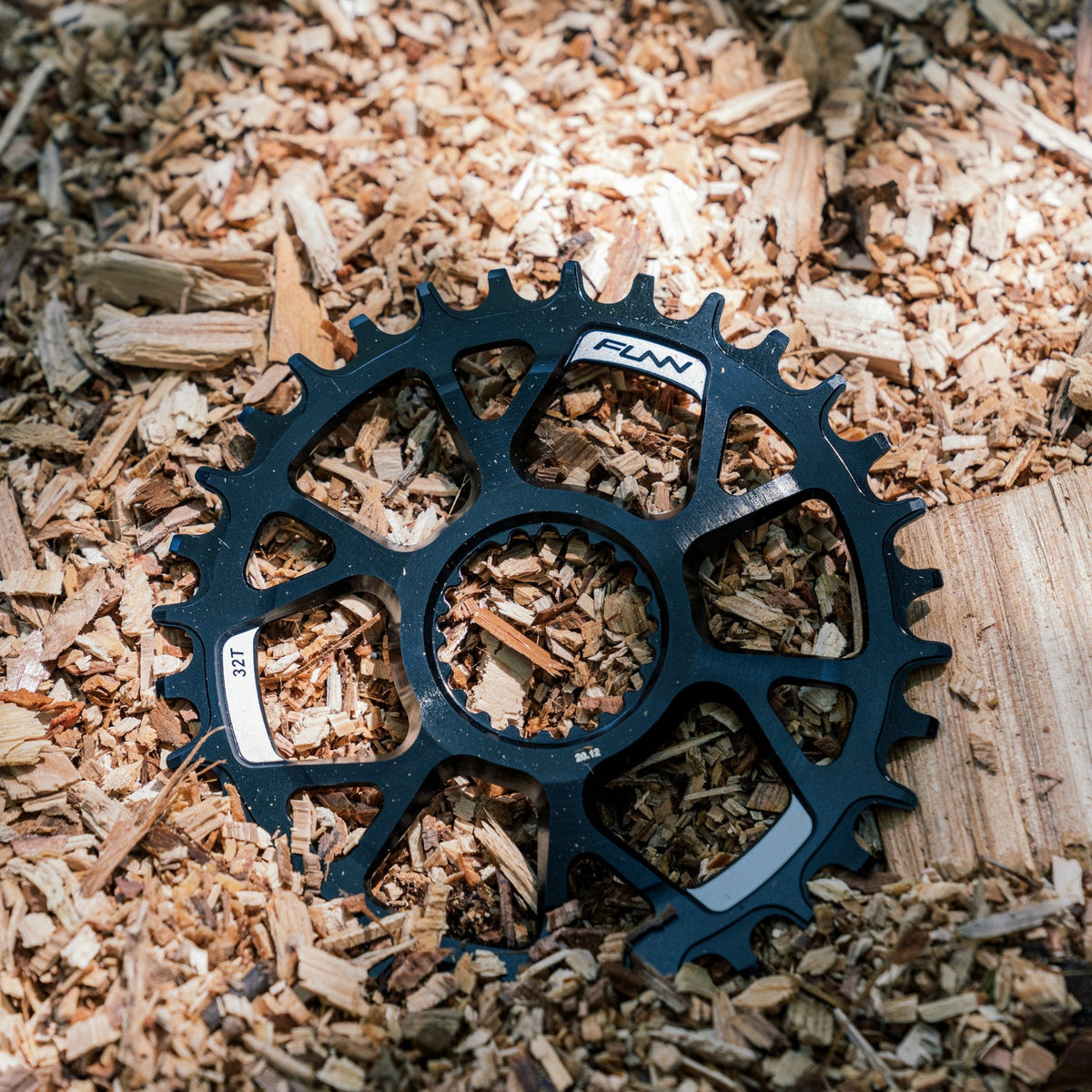 Black aluminum FUNN Solo DS narrow-wide chainring with machined spider design, shown on wood chips for MTB drivetrain use