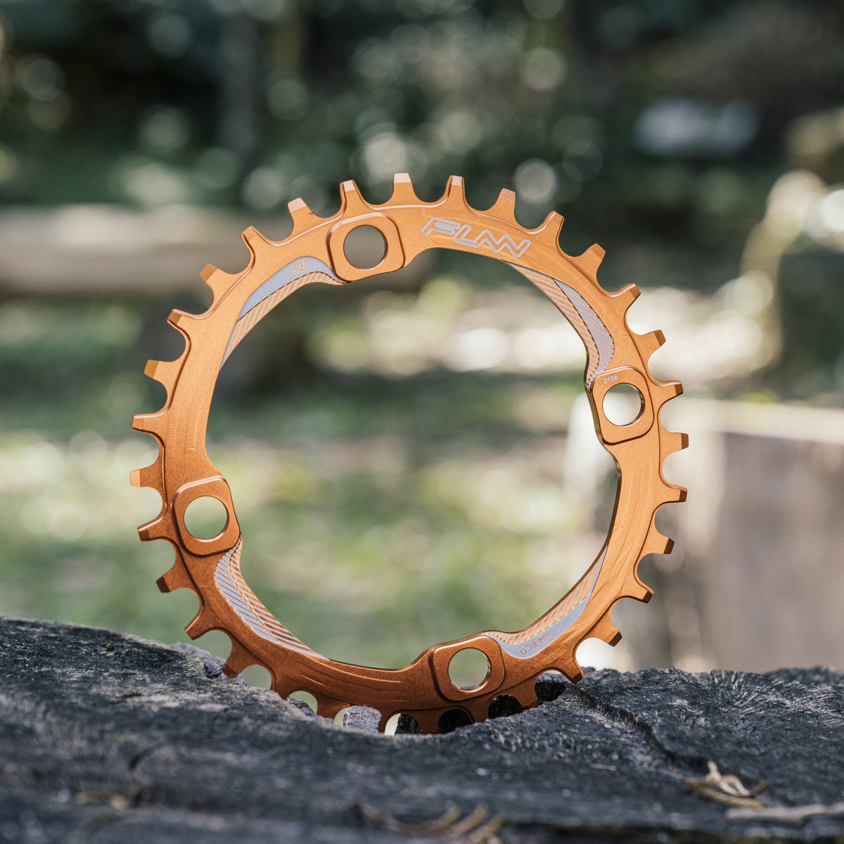 FUNN Solo Narrow-Wide Chainring, orange anodized alloy MTB chainring with narrow-wide teeth design on outdoor stump backdrop