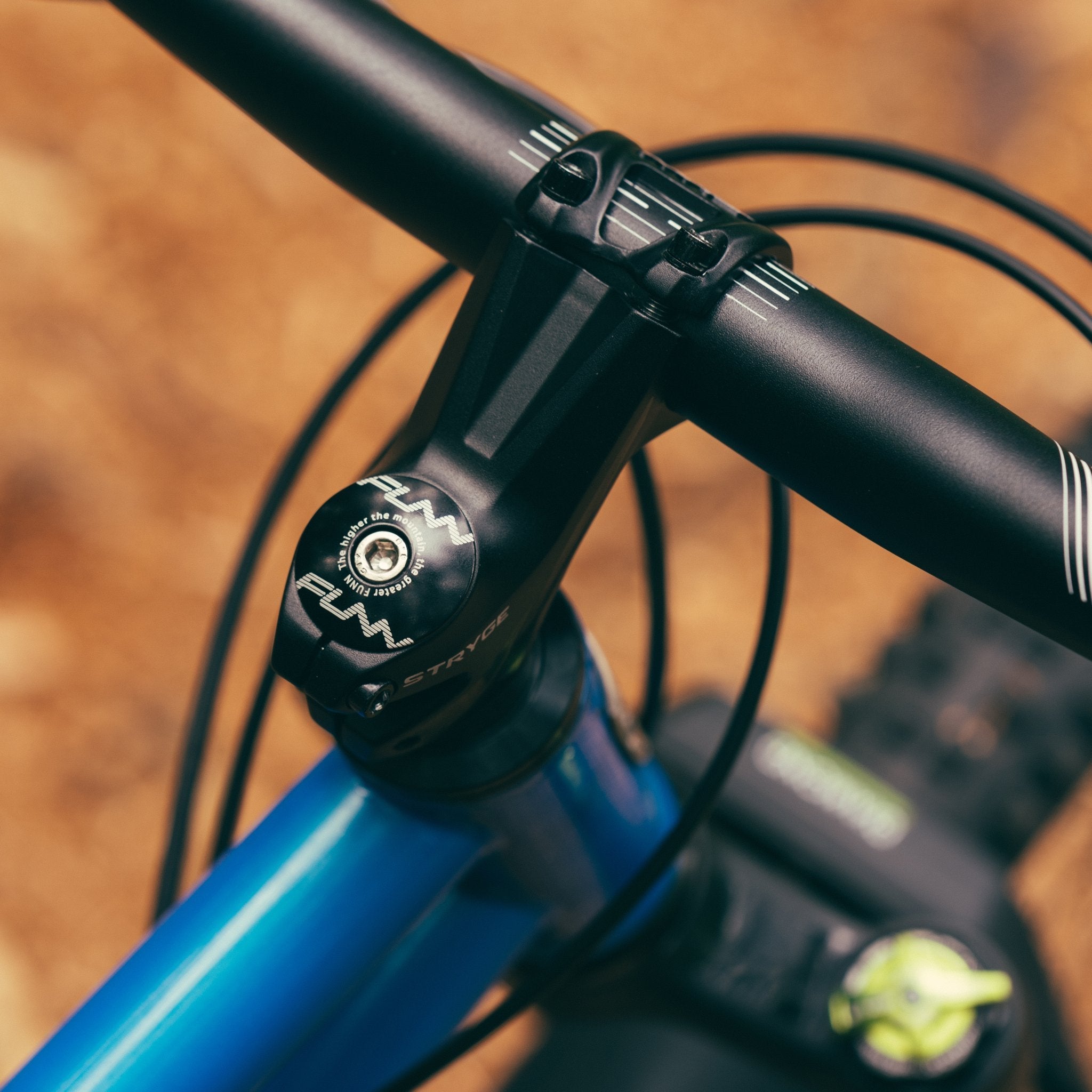 Black aluminum FUNN Stryge rise stem securely clamps flat MTB handlebar on blue trail bike for precise steering control