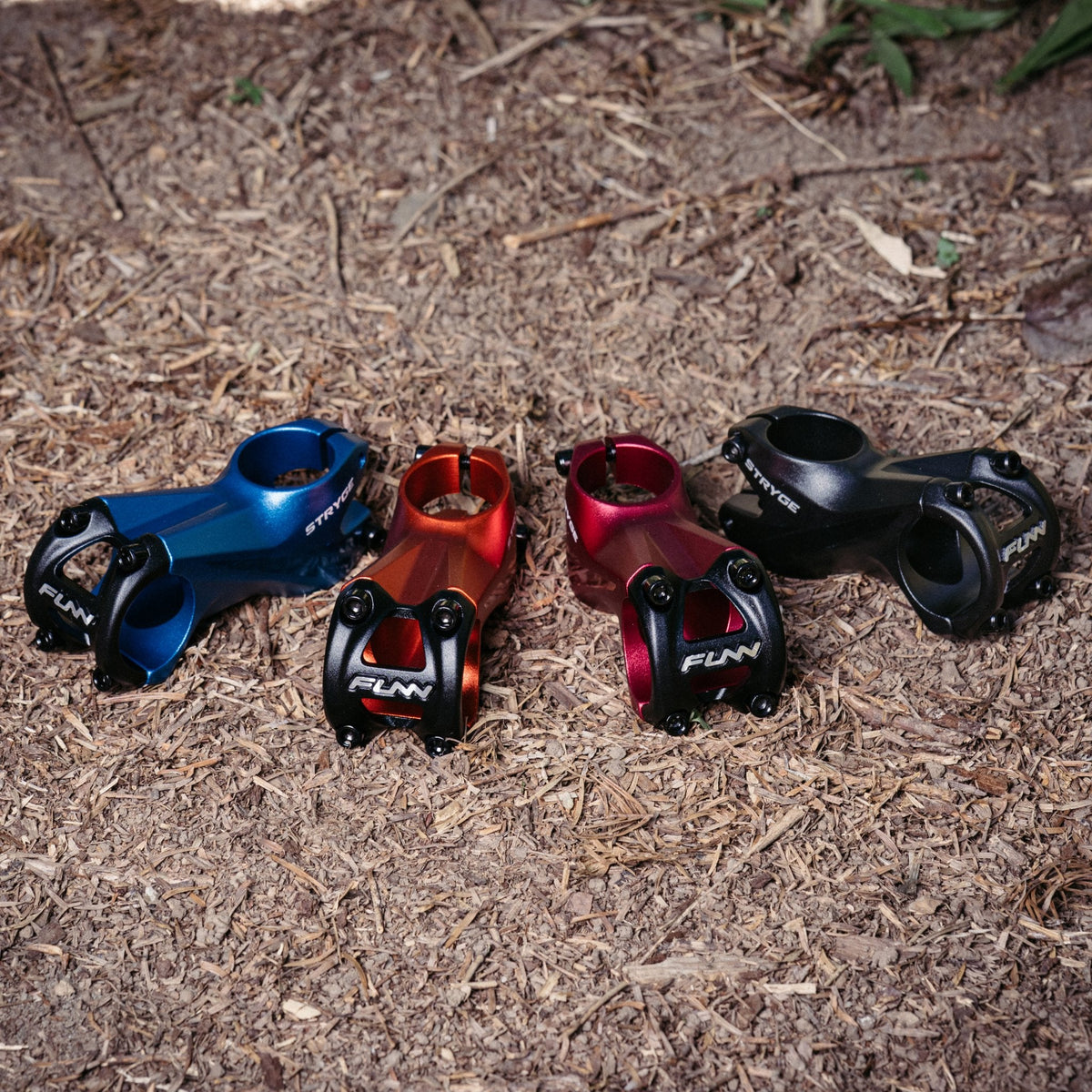 FUNN Stryge Riser Stem range in blue, orange, red and black, CNC alloy mountain bike handlebar stems on trail ground
