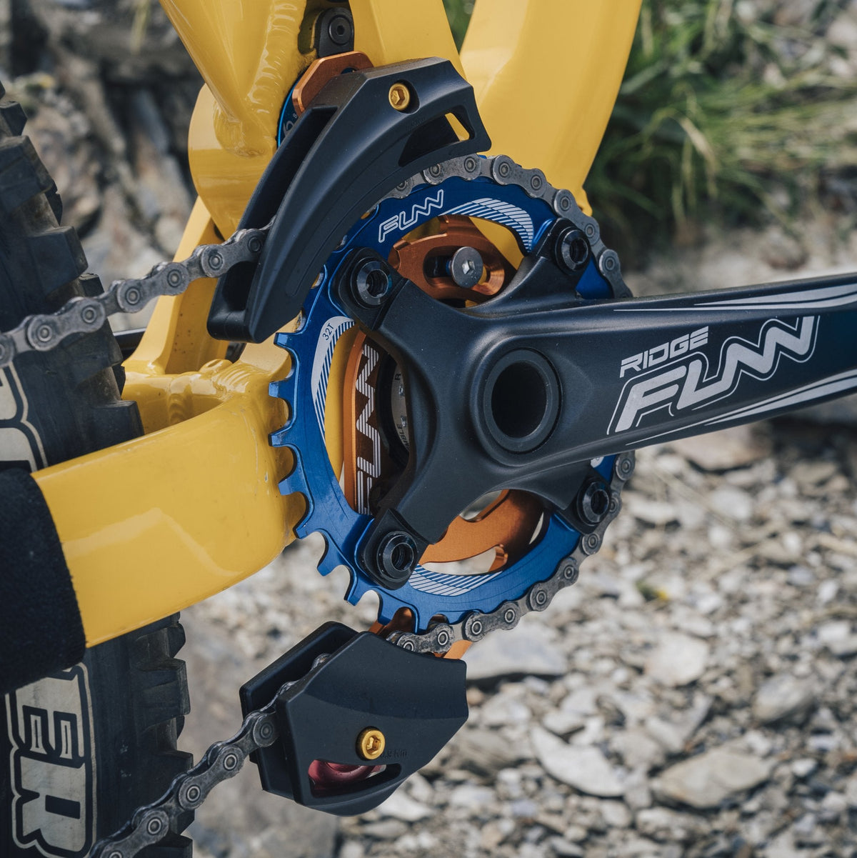 FUNN Zippa AM Chain Guide on mountain bike crankset, black plastic guard with blue and orange alloy ring preventing chain drops