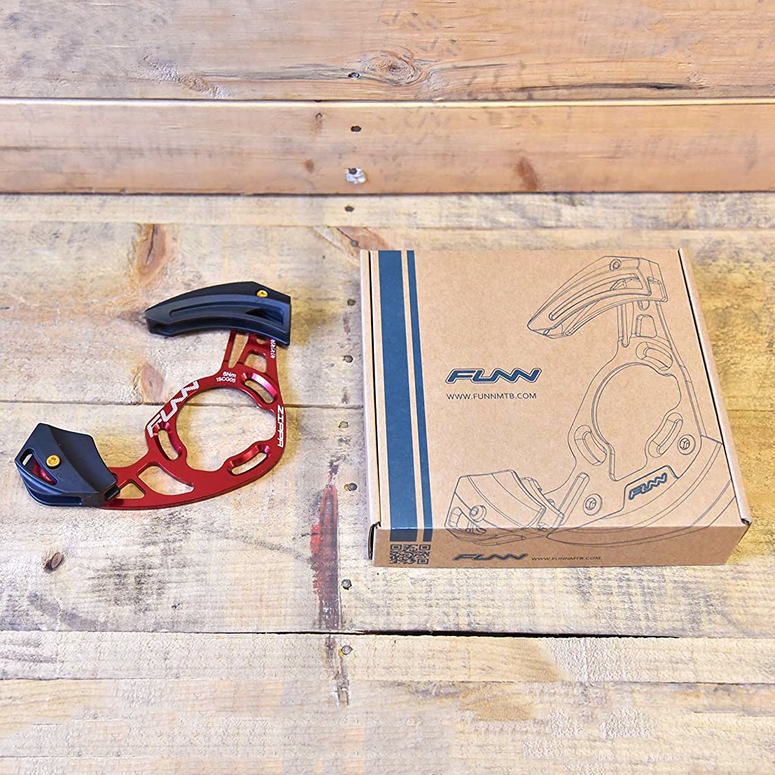 FUNN Zippa AM Chain Guide in red alloy with black guards on wooden table beside branded cardboard packaging