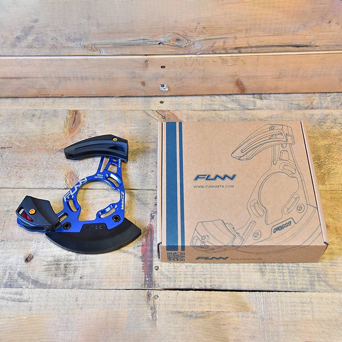 FUNN Zippa DH Chain Guide in blue alloy with black bash guard and box, mountain bike chain retention device on wooden table