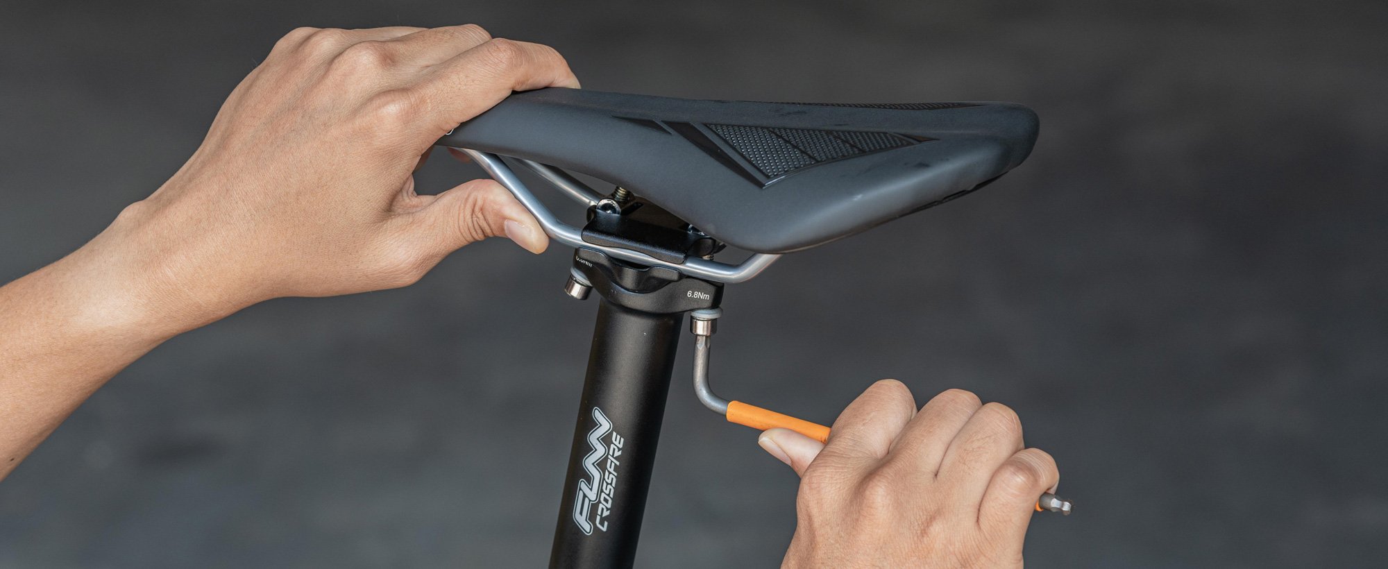 The image shows a person adjusting the funn crossfire seat post for positioning the funn skinny bike saddle using a hex key.slider_item_jYF7rt