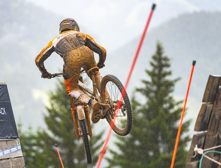 a mountain bike rider on a race track and jumping in the air with his bike