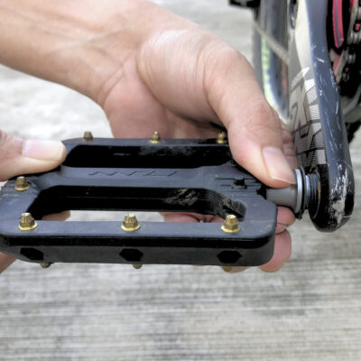 A person is tightening a pedal on a bike by hand.