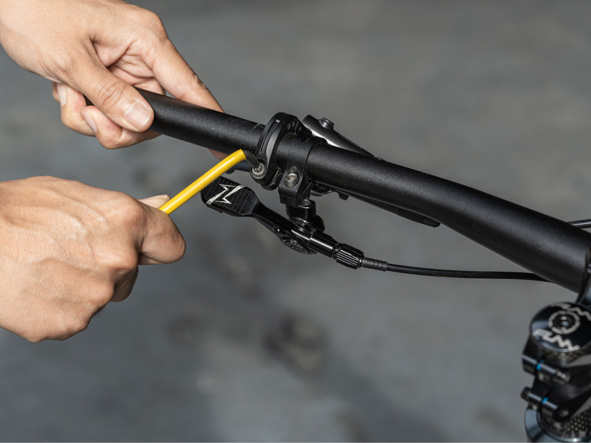 A person is using a yellow tool to adjust the handlebar on a bike.