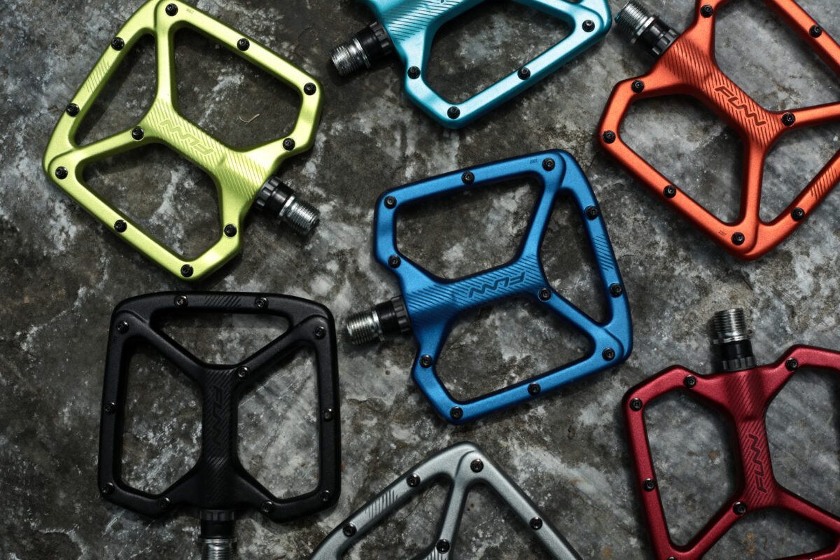 A group of colorful bicycle pedals on a concrete surface.