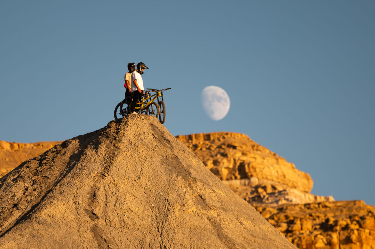 A person standing on top of a mountain with a bike.