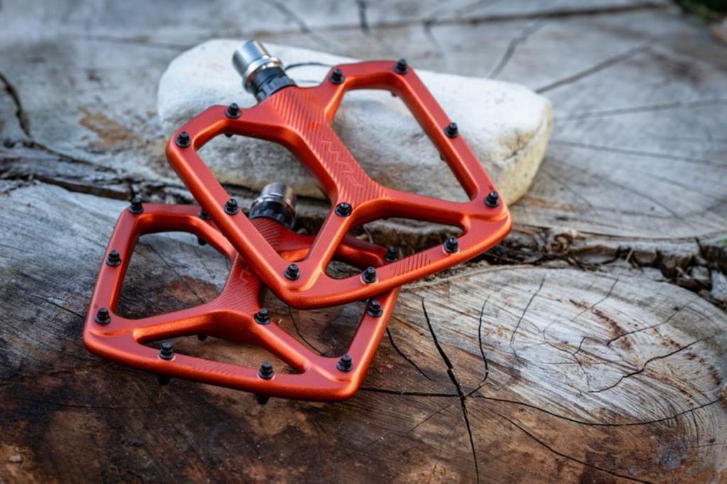 A pair of orange pedals on top of a piece of wood.