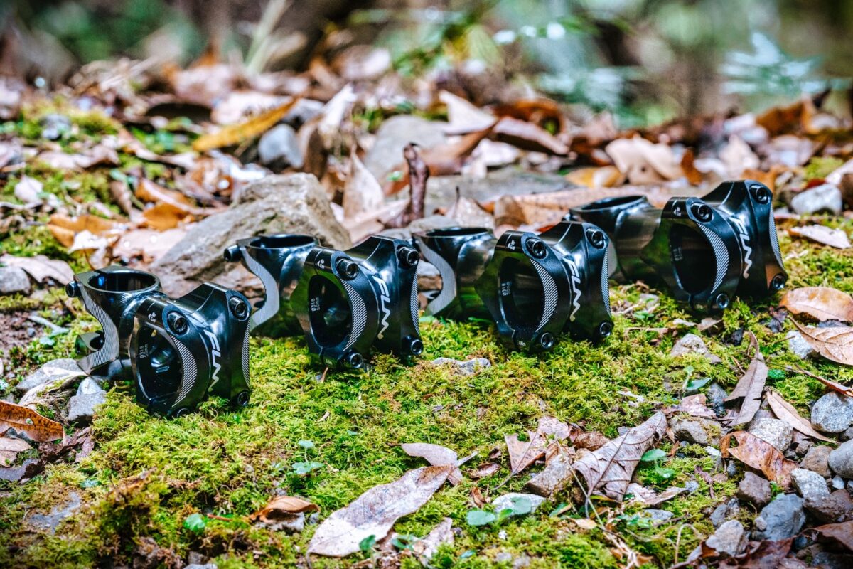Four Funn Tron bike stems in a lineup on mossy ground encircled by fallen leaves